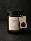 Latimer Goods Black Coffee Candle in deep olive glass jar with ivory label and oxblood wax seal tag on dark background