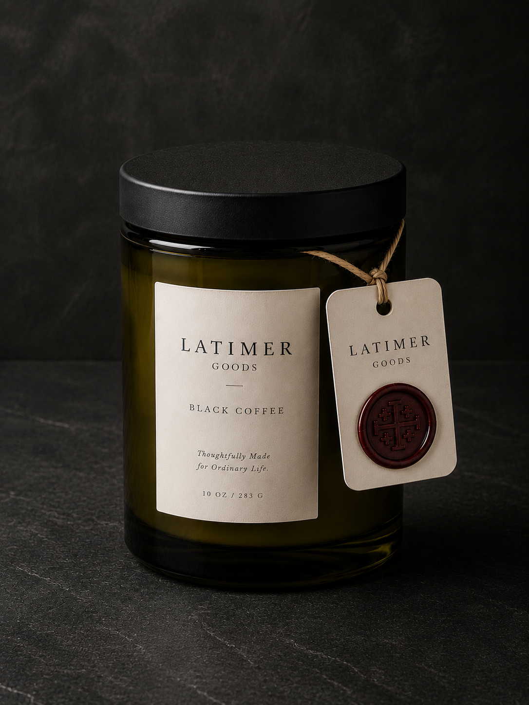 Latimer Goods Black Coffee Candle in deep olive glass jar with ivory label and oxblood wax seal tag on dark background