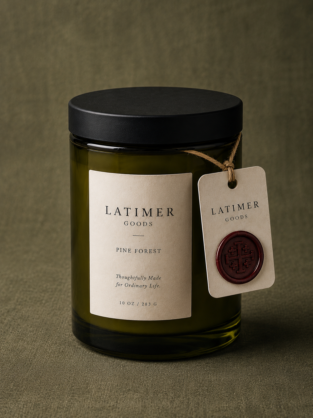 Latimer Goods Pine Forest Candle in olive green glass jar with ivory label and oxblood wax seal tag